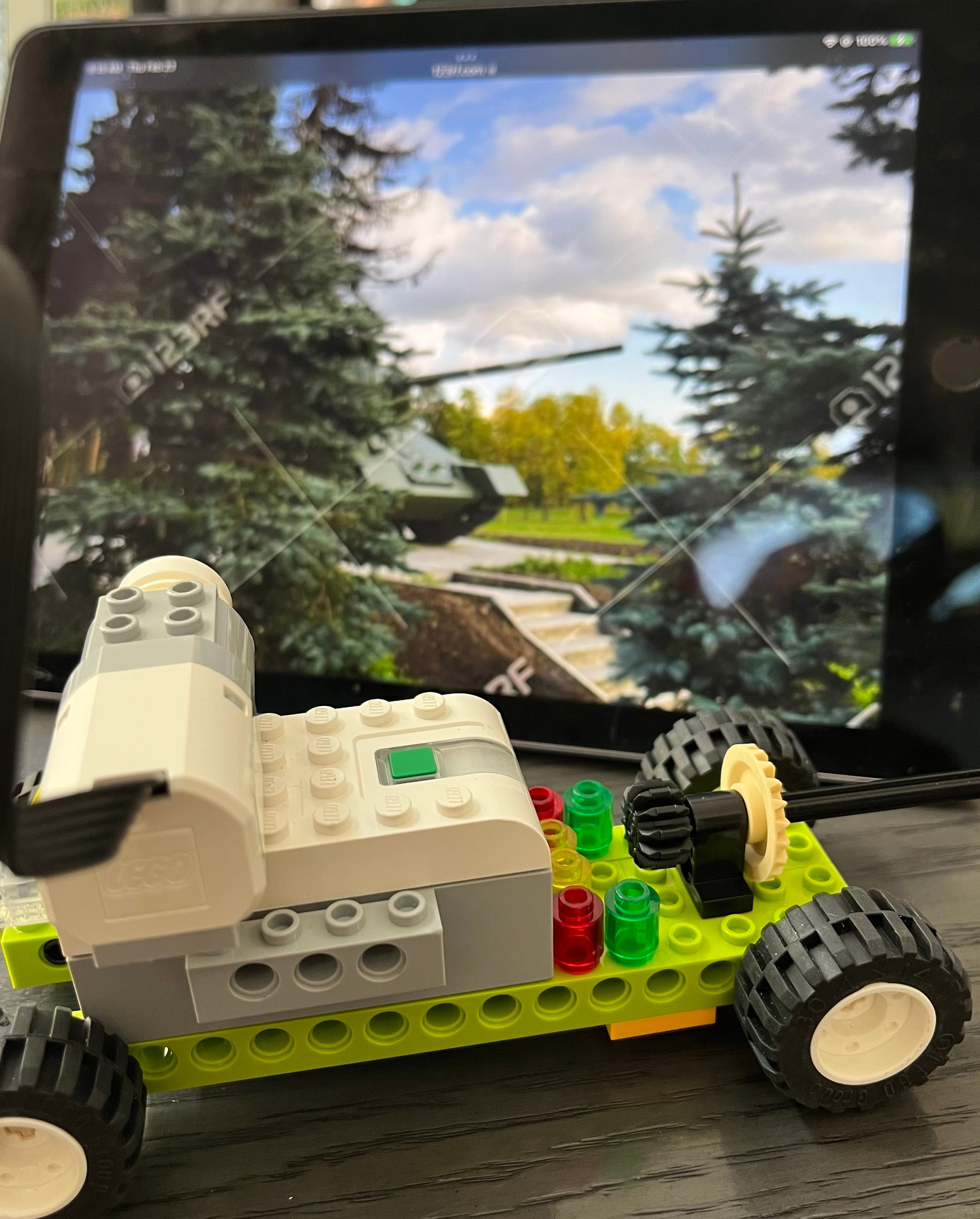 A Lego car with a tablet computer placed on a table, showcasing a playful combination of technology and creativity.
